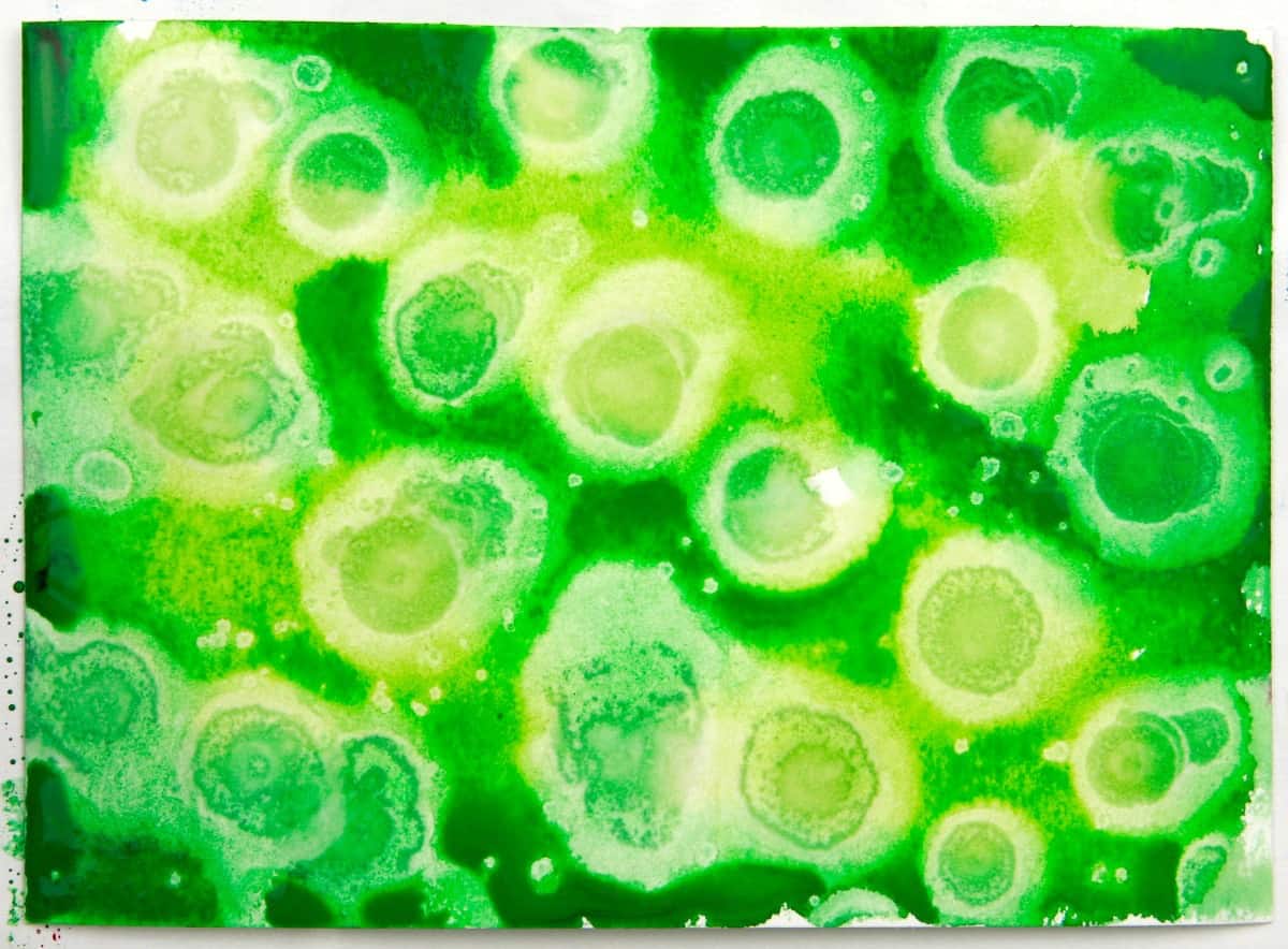 green watercolor paint with rubbing alcohol dripped on