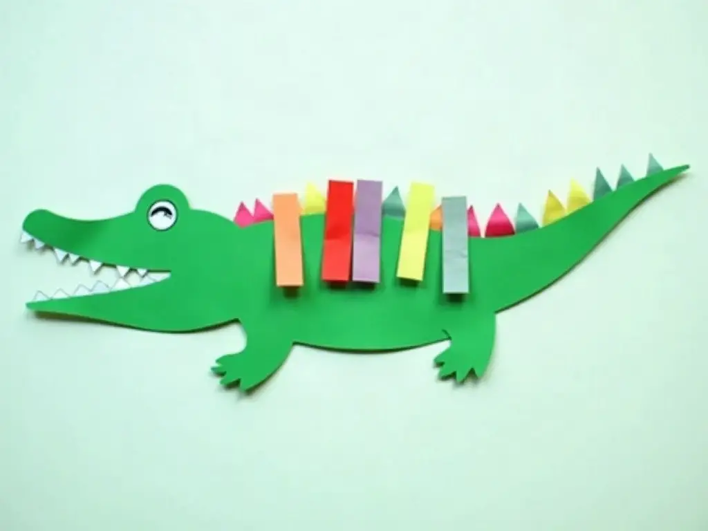 Paper strips being woven through a cut paper crocodile